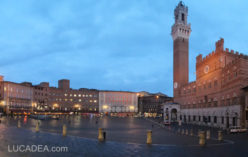 Piazza del Campo a Siena illuminata dalla sera con la Torre del Mangia nel centro storico toscano