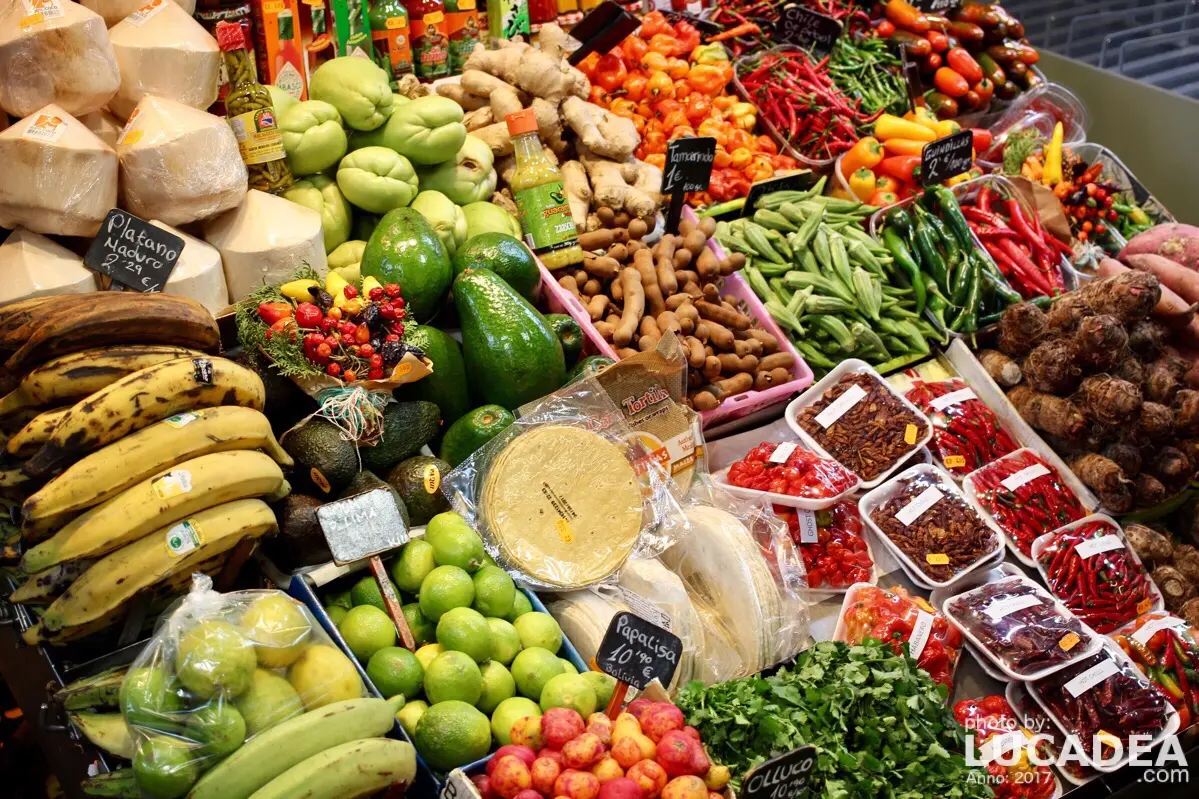 Bancarella di frutta tropicale in un mercato di Barcellona con mango, platani e peperoncini colorati