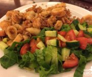 Un piatto con calamari fritti e insalata greca