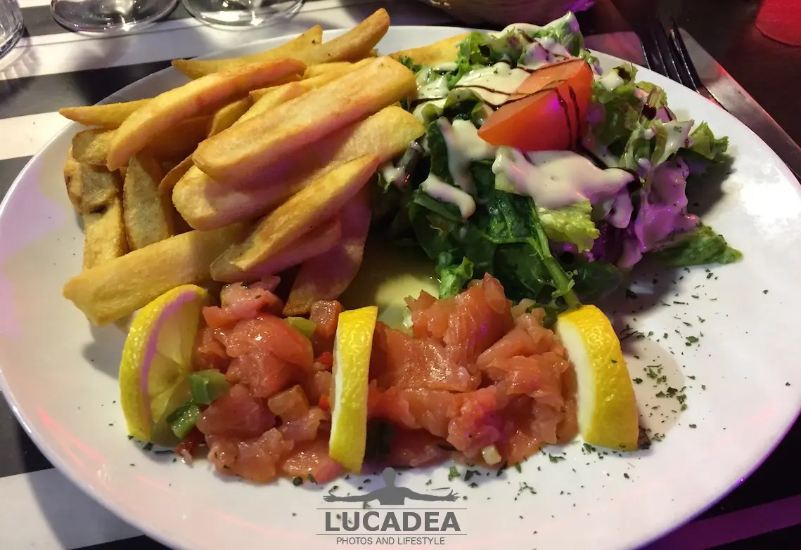 Carpaccio di salmone con limone, olio e contorni di patatine fritte e insalata a Marsiglia