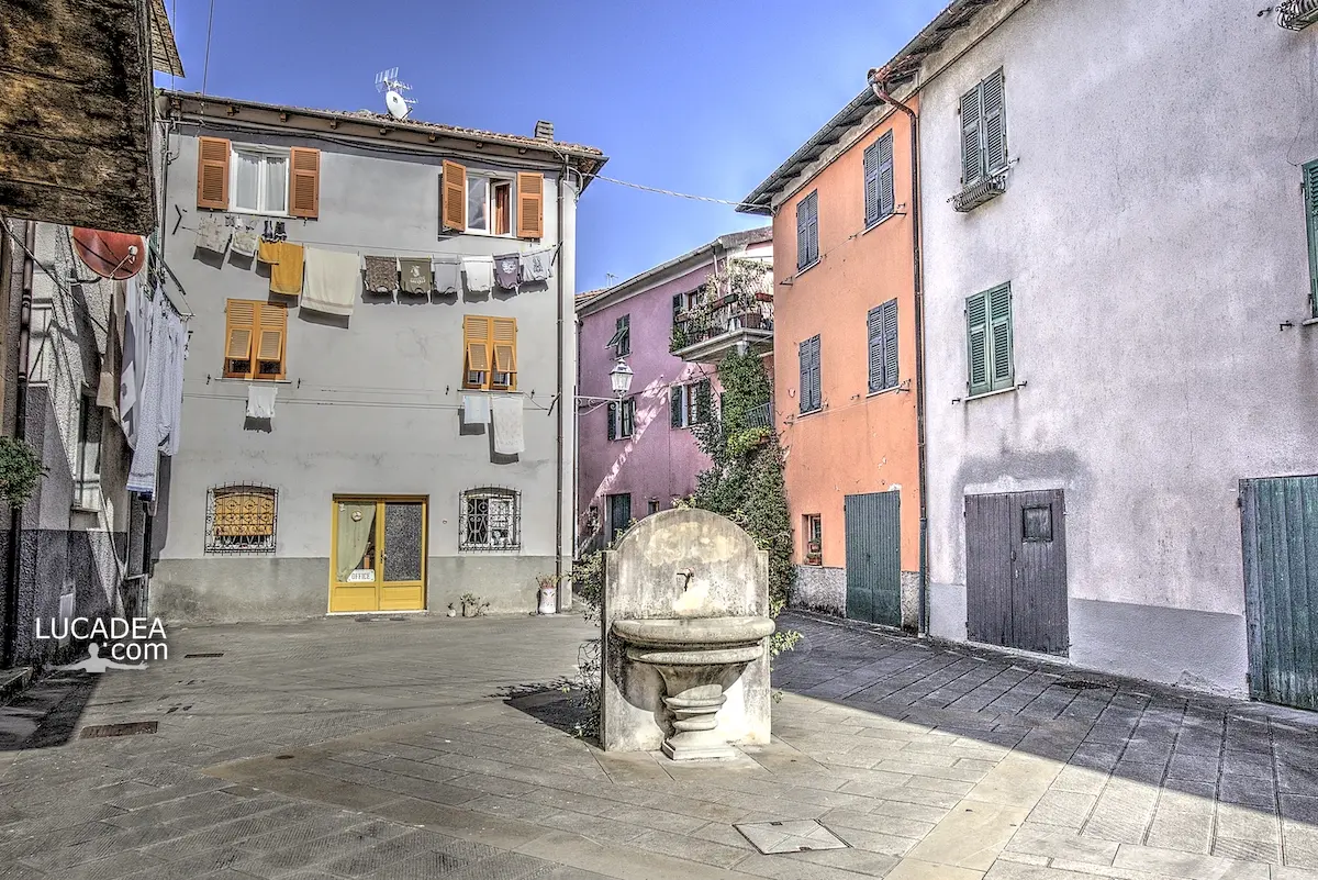 Bella piazzetta con fontana nel borgo di Sesta Godano in Val di Vara lungo il carrugio tra case in pietra