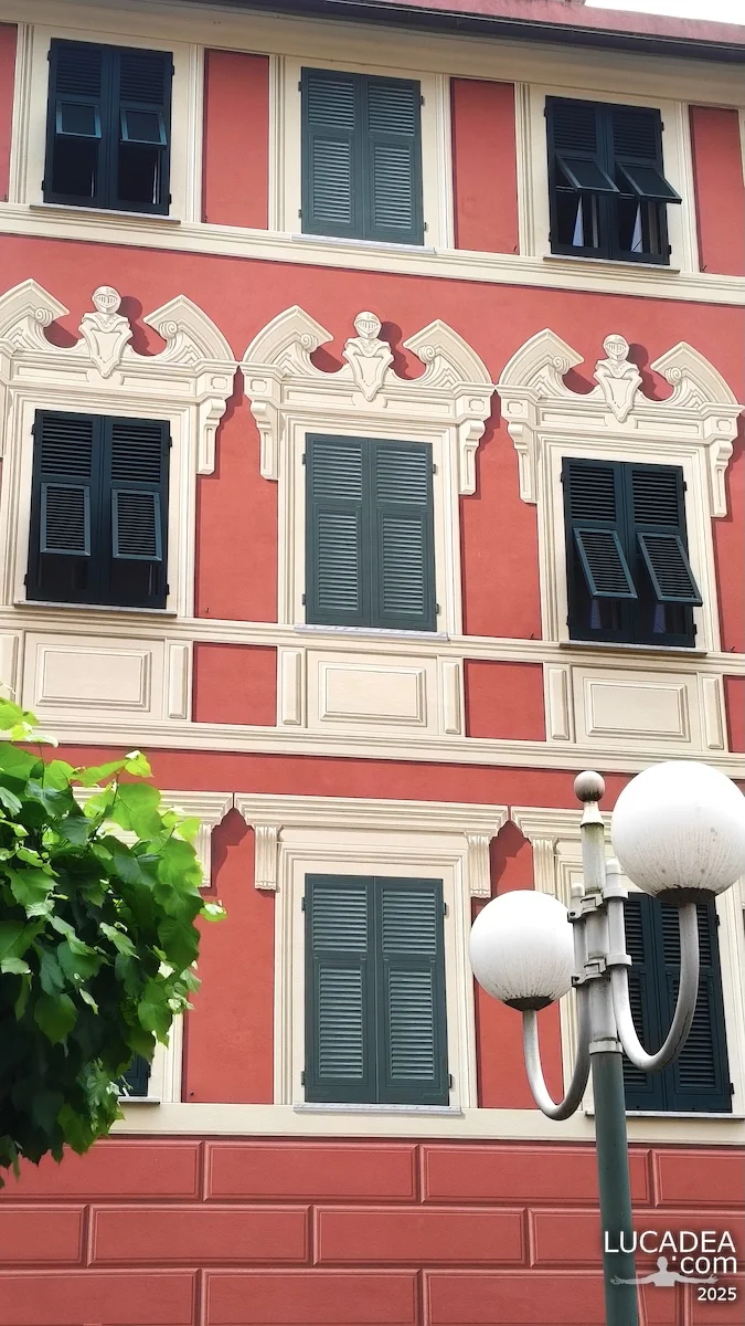 Finestra dipinta a Lavagna su facciata rossa con persiane verdi simulate in stile trompe-l’œil tipico ligure