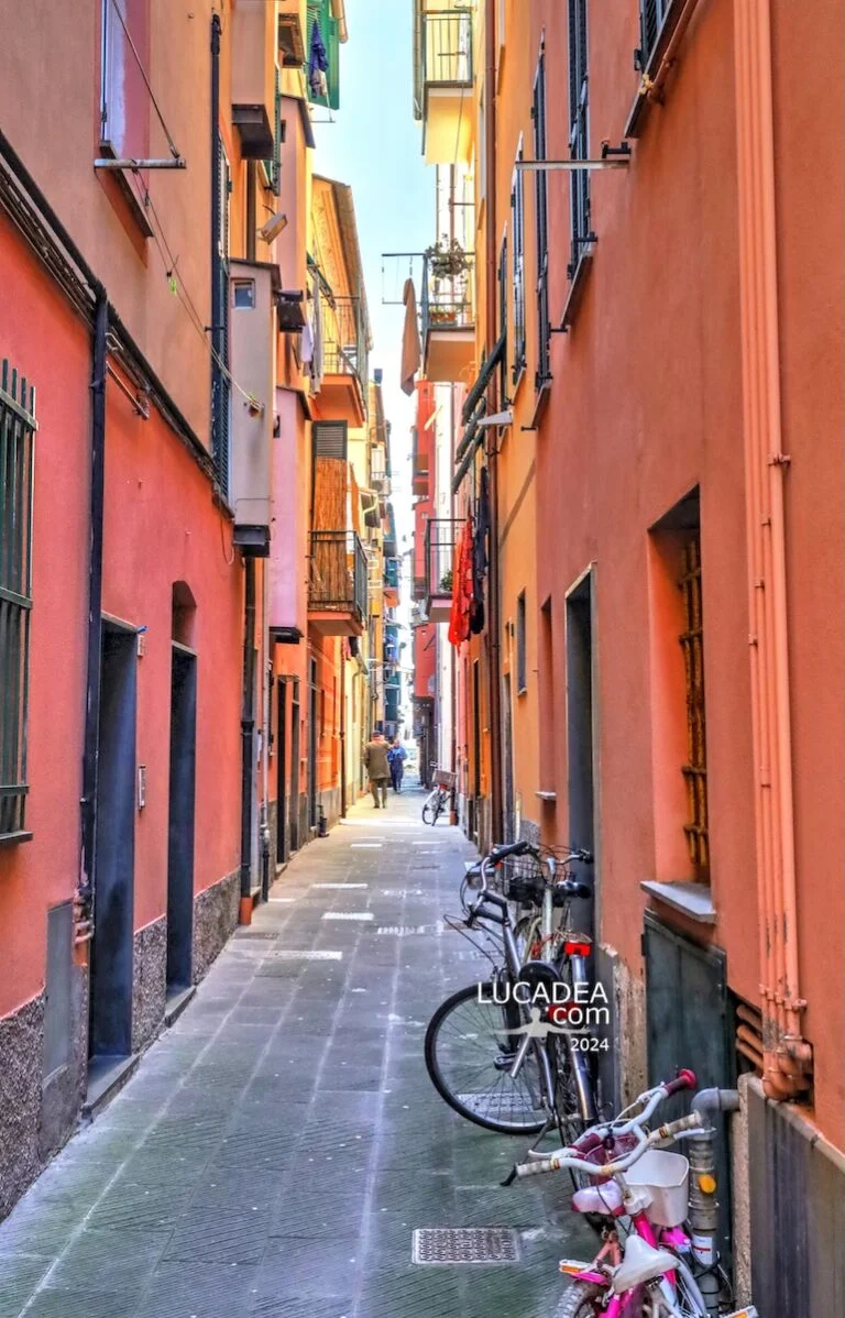 Vicolo stretto nel centro storico di Lavagna con case colorate, biciclette parcheggiate, panni stesi e luce naturale diffusa tra gli edifici