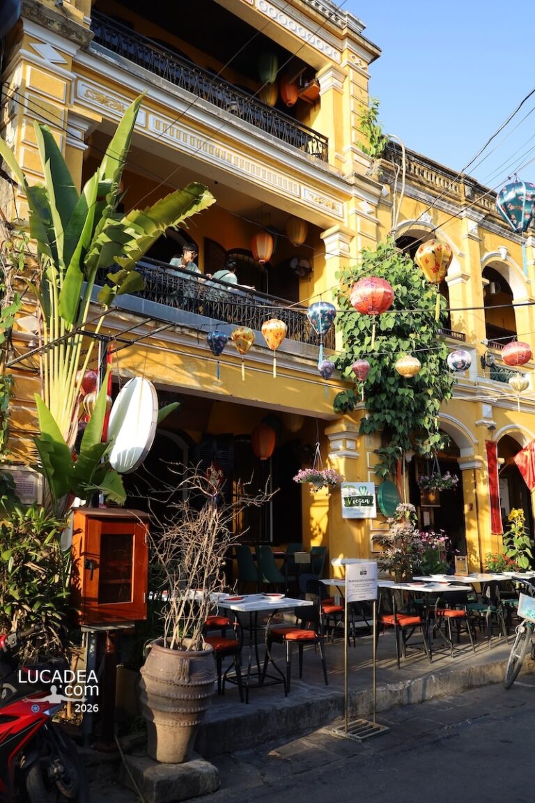 Casa gialla a Hoi An con lanterne e piante sospese, edificio tradizionale trasformato in café nel centro storico vietnamita