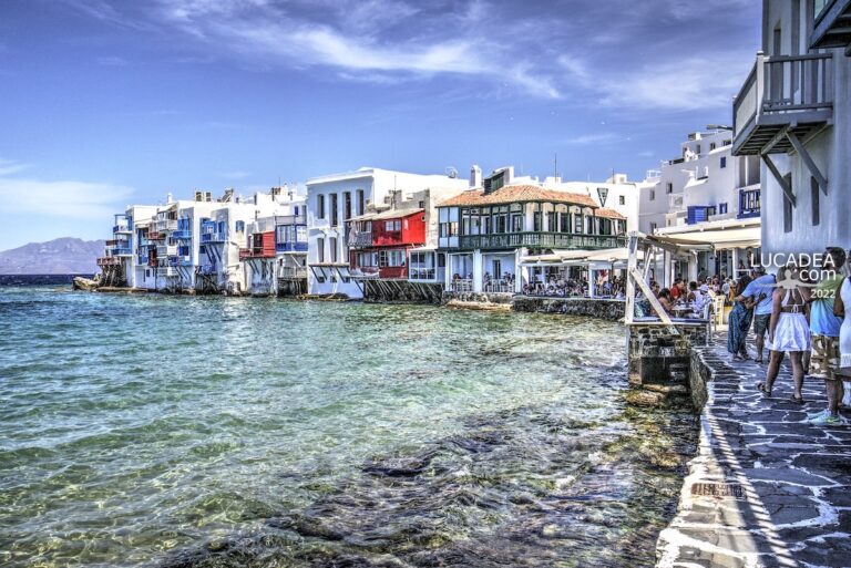 Case sul mare a Little Venice Mykonos con balconi colorati affacciati sull’acqua limpida e passeggiata con persone