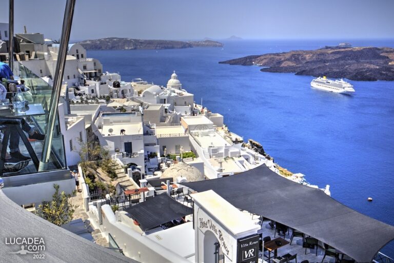 Vista sulla caldera di Santorini con case bianche e nave da crociera nel mare blu intenso delle Cicladi
