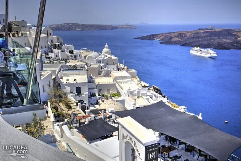 Vista sulla caldera di Santorini con case bianche e nave da crociera nel mare blu intenso delle Cicladi