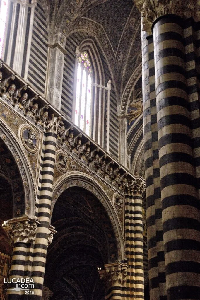 Dettagli delle colonne e capitelli nelle navate laterali del duomo di Siena con decorazioni in marmo bianco e nero