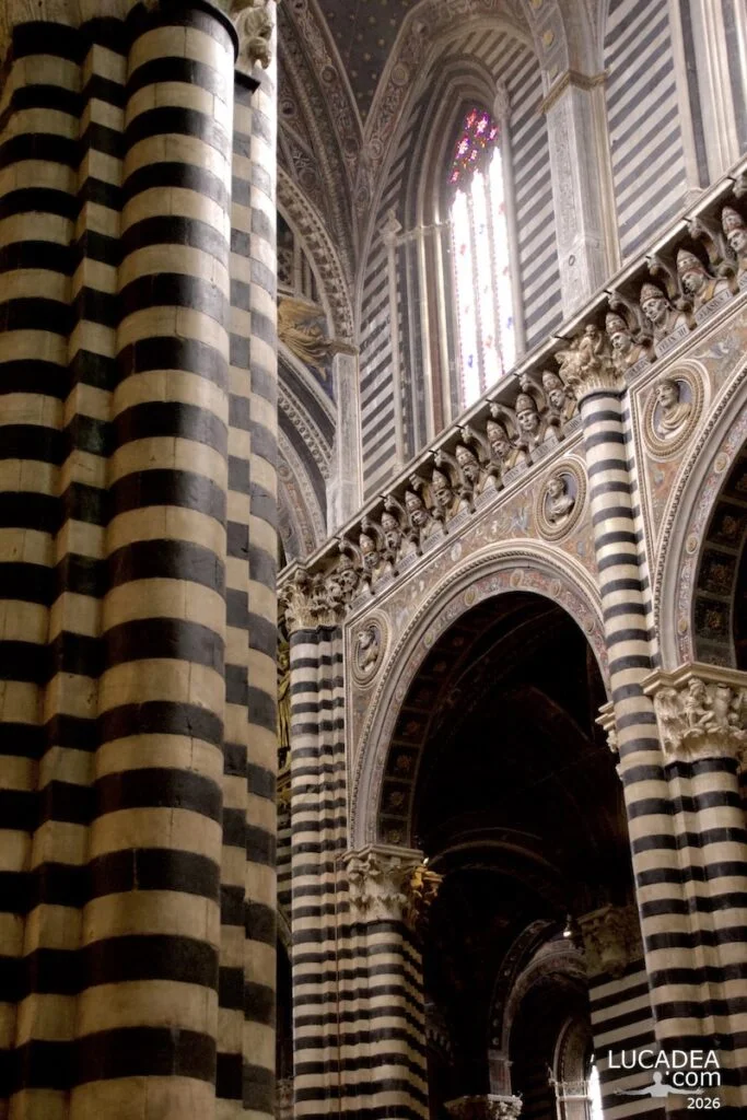 Dettagli delle colonne e capitelli nelle navate laterali del duomo di Siena con decorazioni in marmo bianco e nero