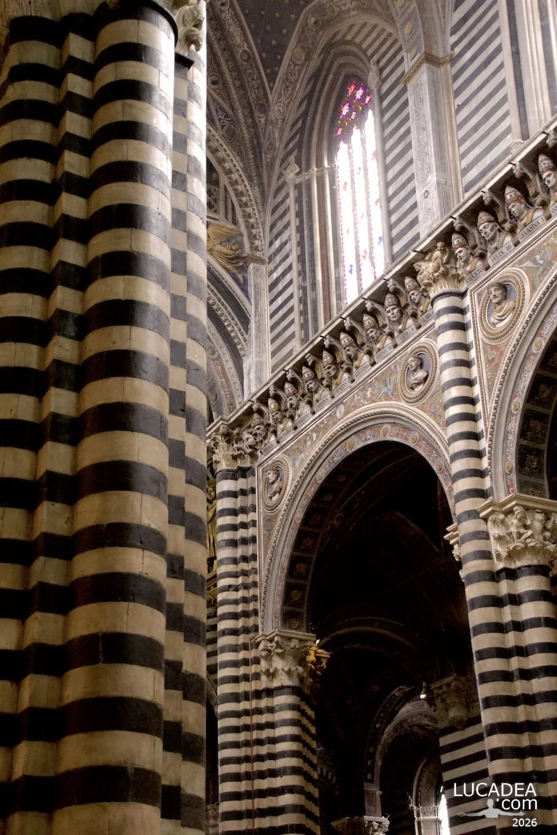 Dettagli delle colonne e capitelli nelle navate laterali del duomo di Siena con decorazioni in marmo bianco e nero