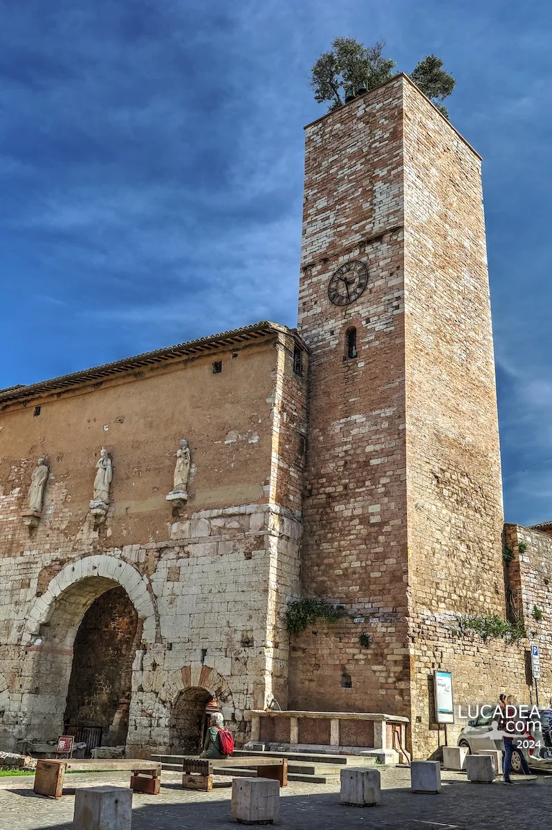 Porta Consolare di Spello con torre annessa, orologio e albero sulla sommità in Umbria