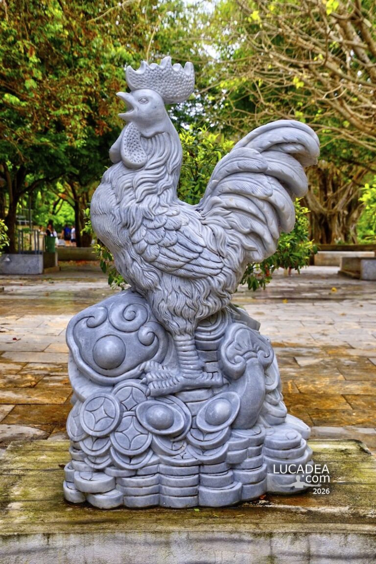 Statua del gallo a Linh Ung Pagoda a Da Nang in Vietnam con base decorata e contesto naturale del tempio buddhista