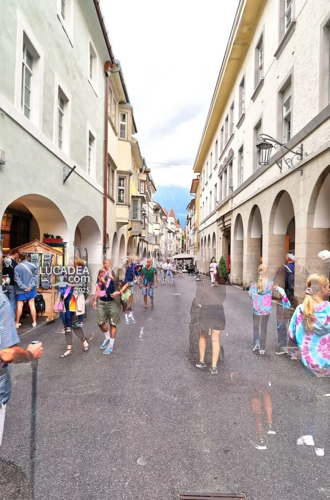 Via Portici a Merano con portici storici, persone in movimento e prospettiva urbana nel centro storico del Trentino-Alto Adige